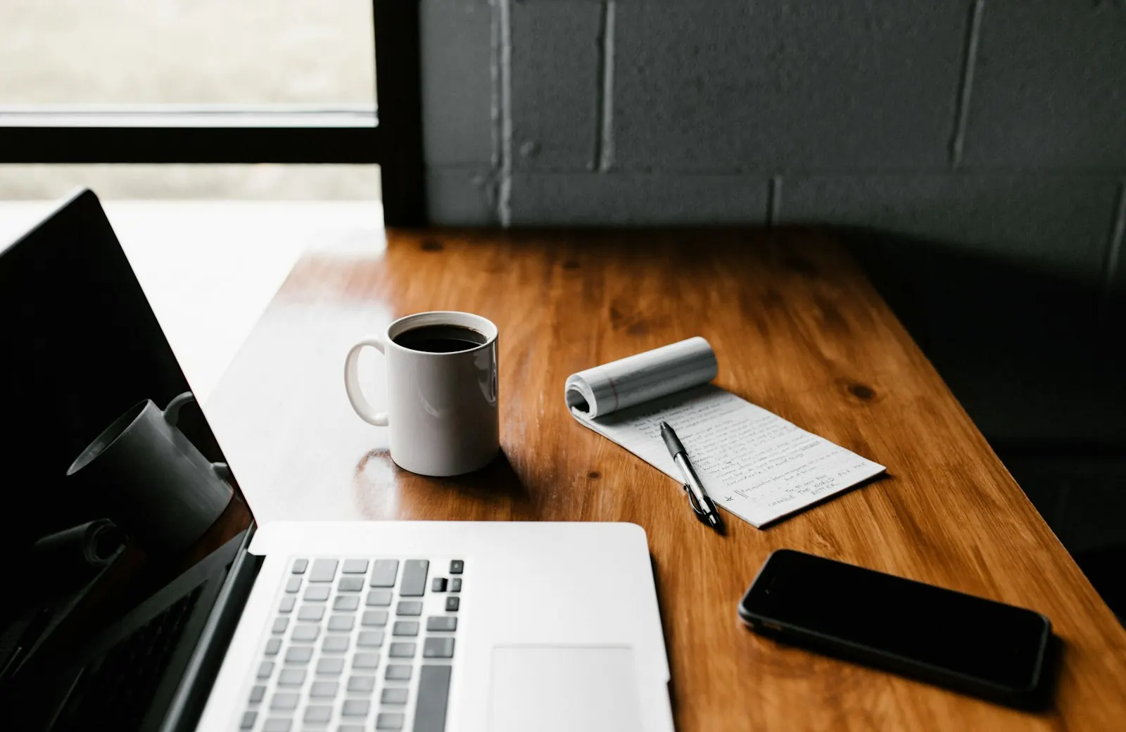 Un ordinateur portable ouvert et un carnet sur une table en bois