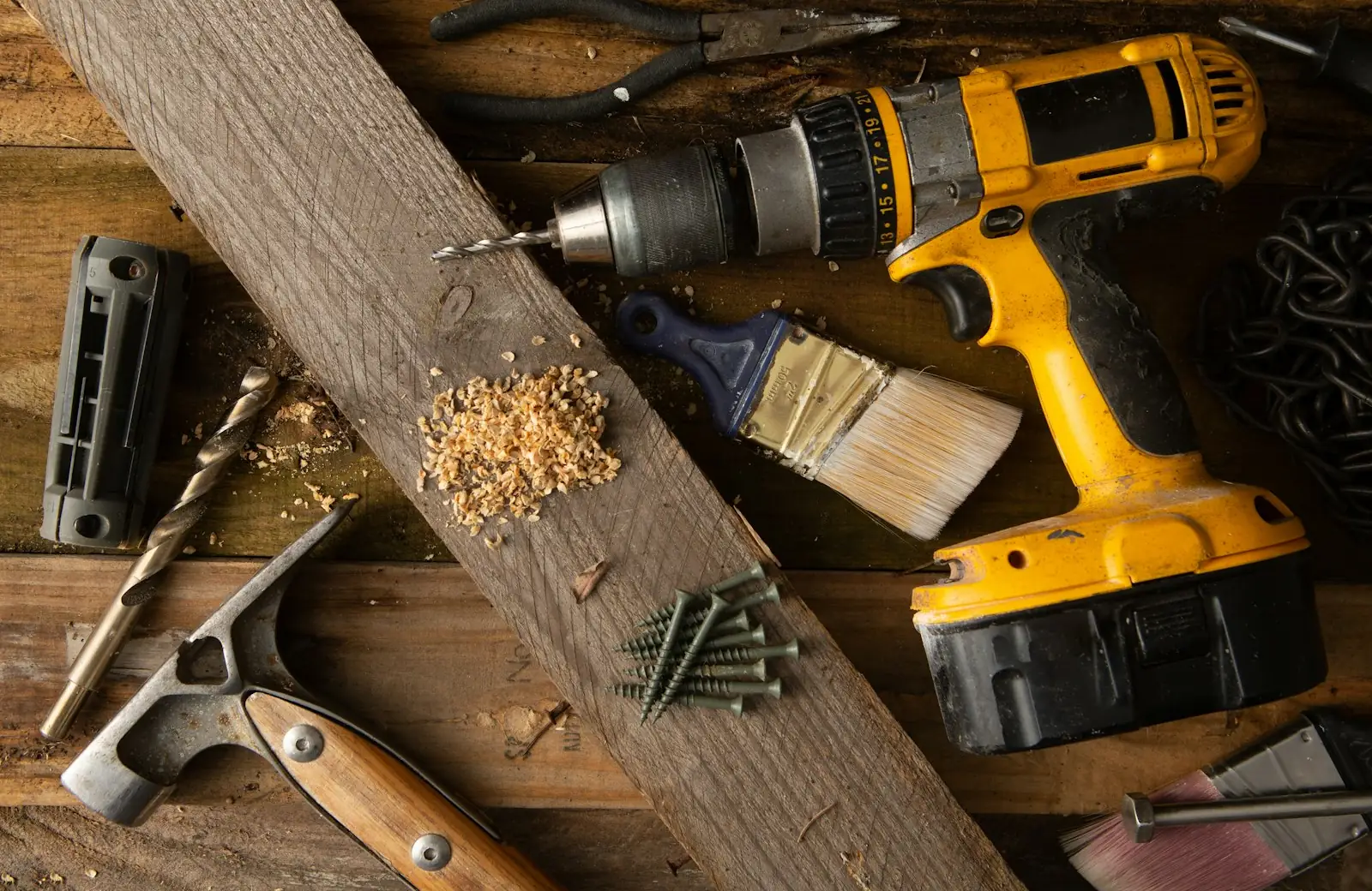 Une perceuse-visseuse posée sur une planche, copeaux de bois autour